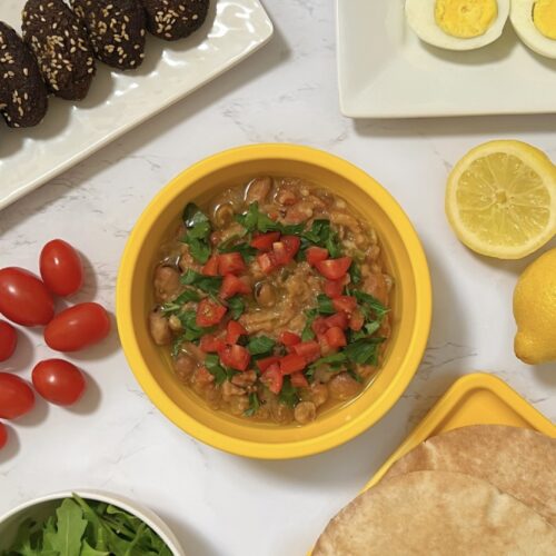 Egyptian ful (fava beans), tameya, eggs, arugula salad, tomatoes, lemon