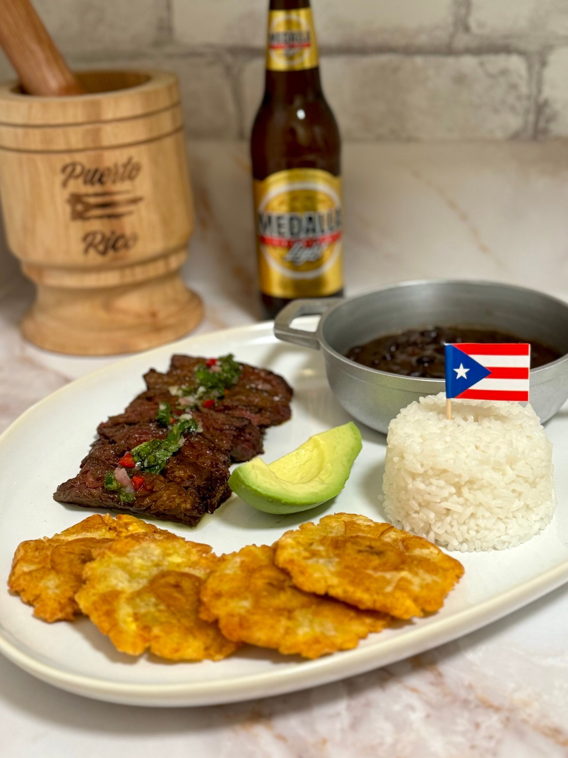 Churrasco with chimichurri sauce, white rice, black beans, tostones, and avocado