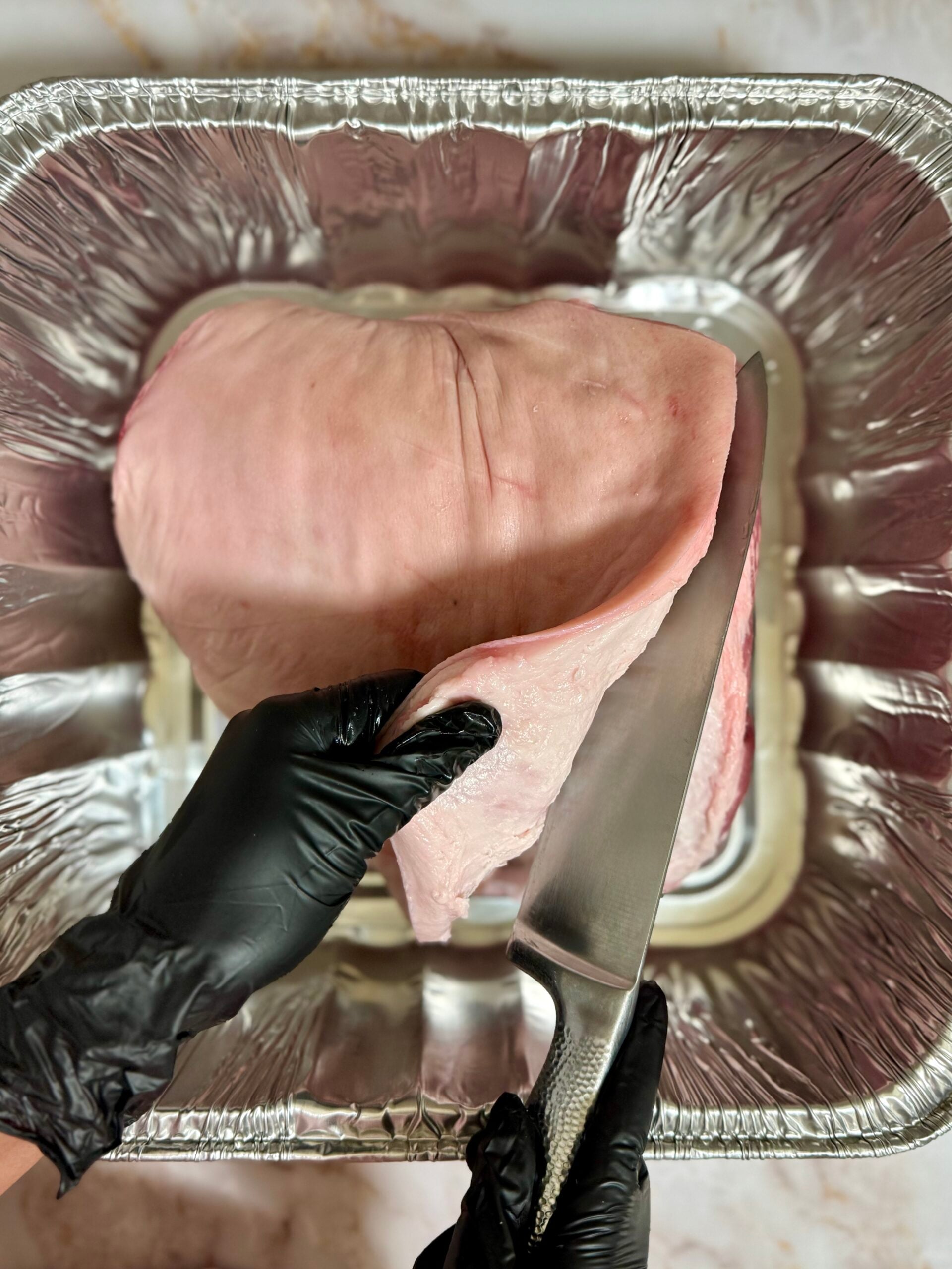 Slicing skin off pernil